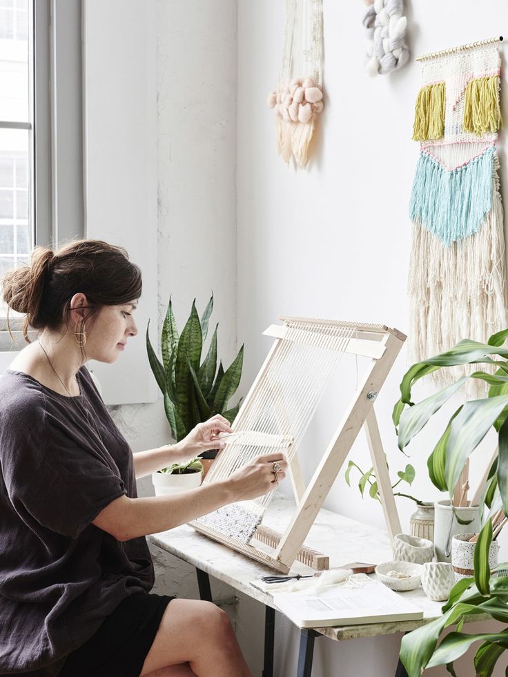 a woman sitting at a desk working on an art project in front of a window