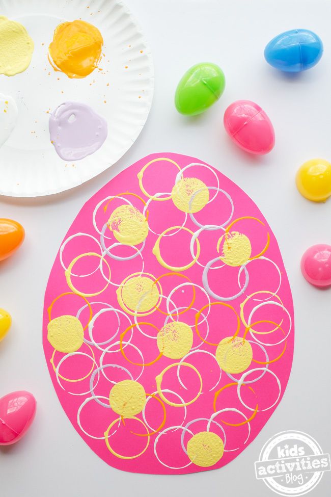 a paper plate with circles painted on it next to some colored eggs and paintbrushes