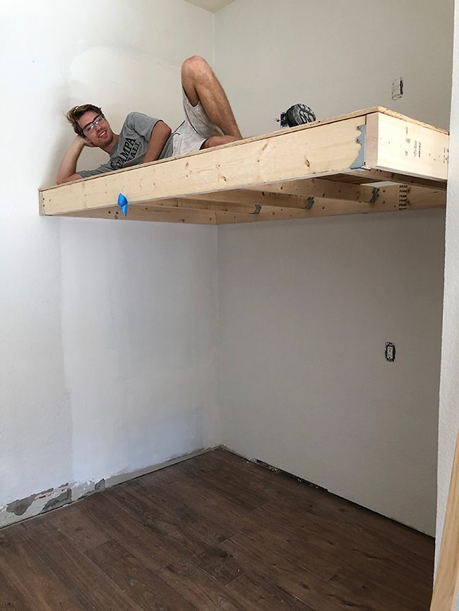 a man laying on top of a wooden bunk bed in a room with hard wood flooring