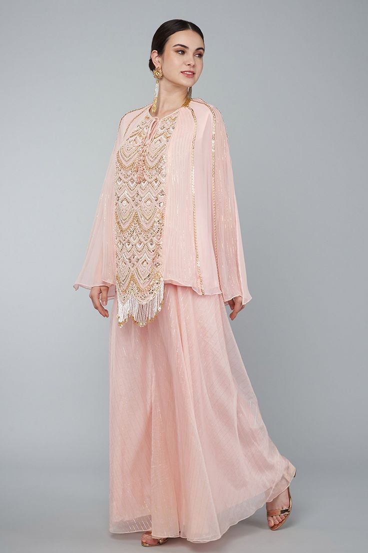 Blush pink georgette panelled embroidered lined tunic with pearls, zari work in art deco motifs and tassel details. Comes with gold zari palazzo.
Component: 2
Pattern: Embroidery
Type Of Work: Pearl,zari
Neckline: Round
Sleeve Type: Split sleeves
Fabric: Georgette,Organza
Color: Pink
Other Details: 
Pearl,zari embroidery
Art deco motifs
Tassel details
Occasion: Destination Wedding - Aza Fashions Embellished Georgette Palazzo Set With Long Sleeves, Embellished Long Sleeve Palazzo Set In Georgette, Elegant Georgette Kurta With Sequins, Elegant Pink Blouse With Sheer Dupatta, Designer Georgette Blouse With Pearl Embroidery, Pearl Embroidered Georgette Kurta For Reception, Festive Designer Georgette Sets, Designer Georgette Sets For Festive Occasions, Designer Festive Sets In Georgette