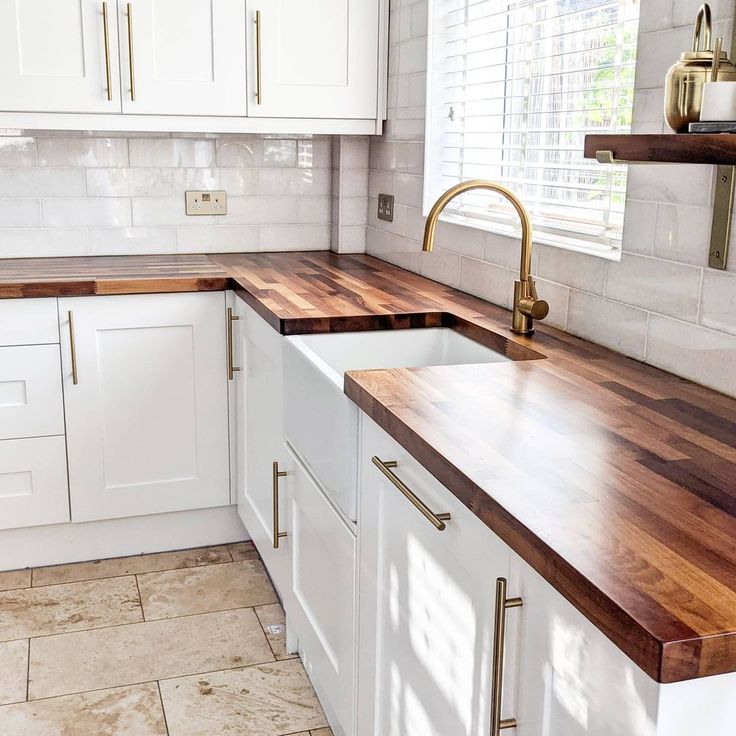 a kitchen with white cabinets and wooden counter tops