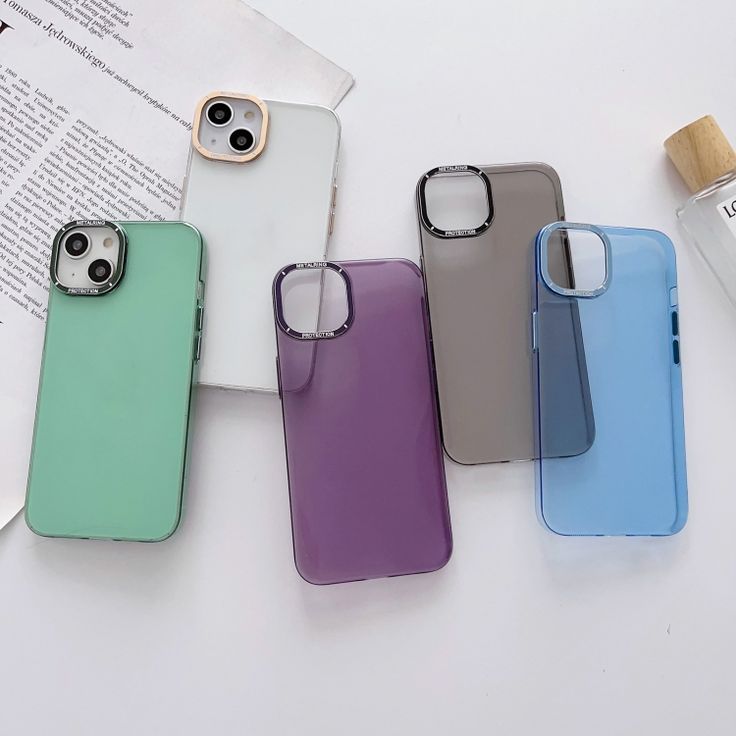 four different colored cases sitting next to each other on top of a white table with an open book