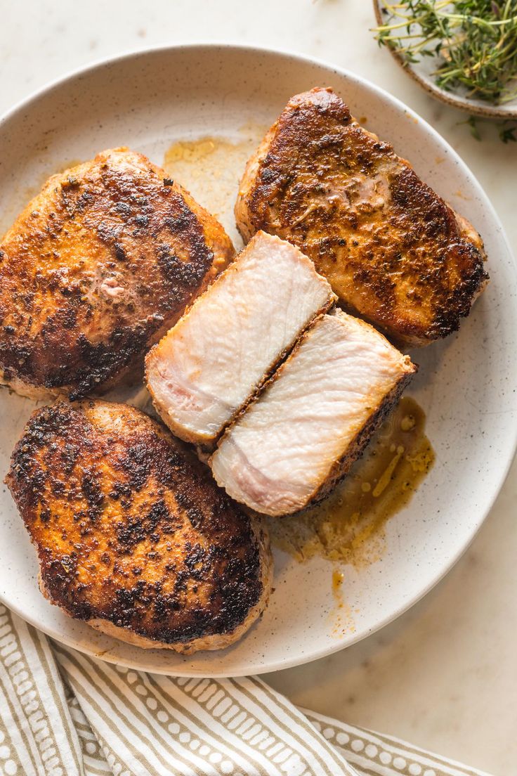 four pieces of fish on a plate with mustard and seasoning next to the dish