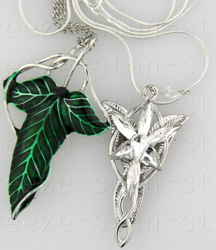 a green leaf is attached to a silver necklace with a star and cross on it