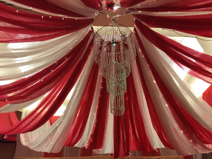 a chandelier hanging from the ceiling with red and white drapes