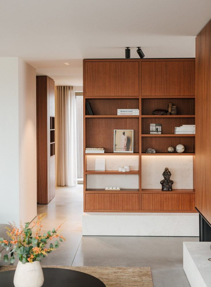 a living room filled with furniture next to a tall wooden book shelf on top of a hard wood floor