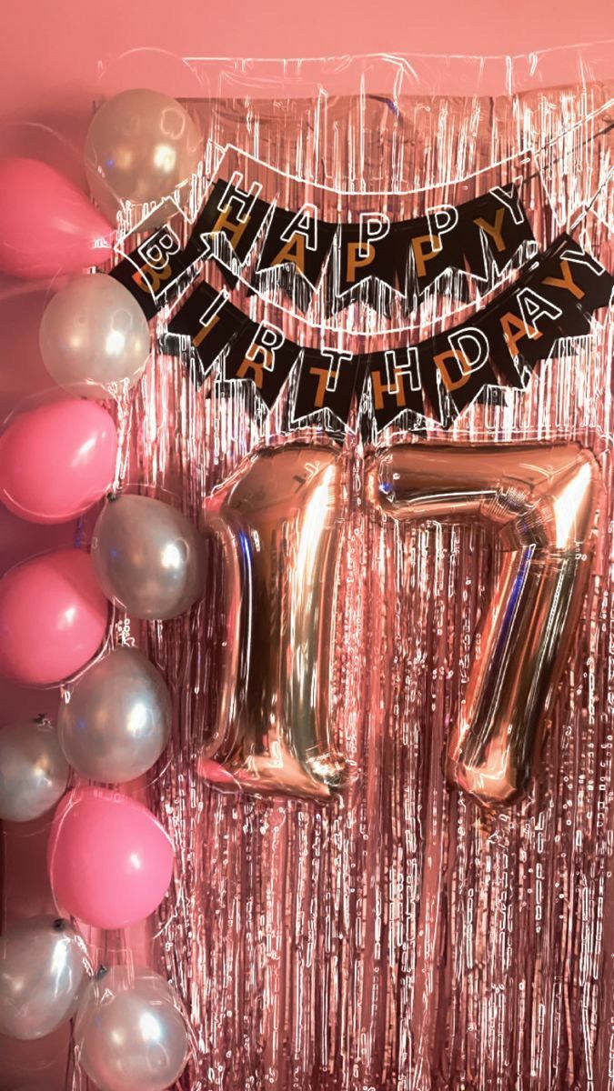 balloons and streamers are arranged in front of a pink backdrop with the number seven