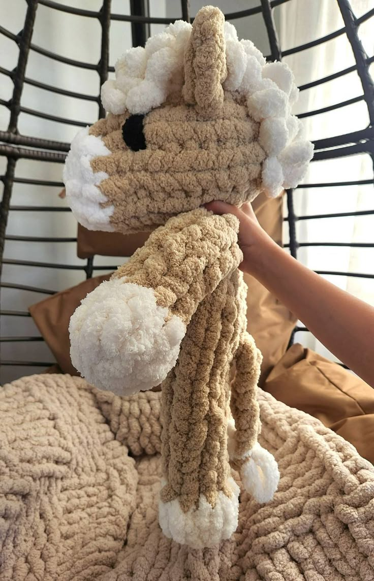 a person holding a stuffed animal on top of a bed next to a pillow and blanket