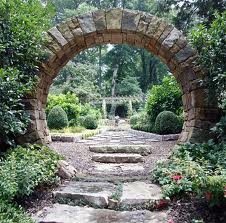 a stone arch in the middle of a garden