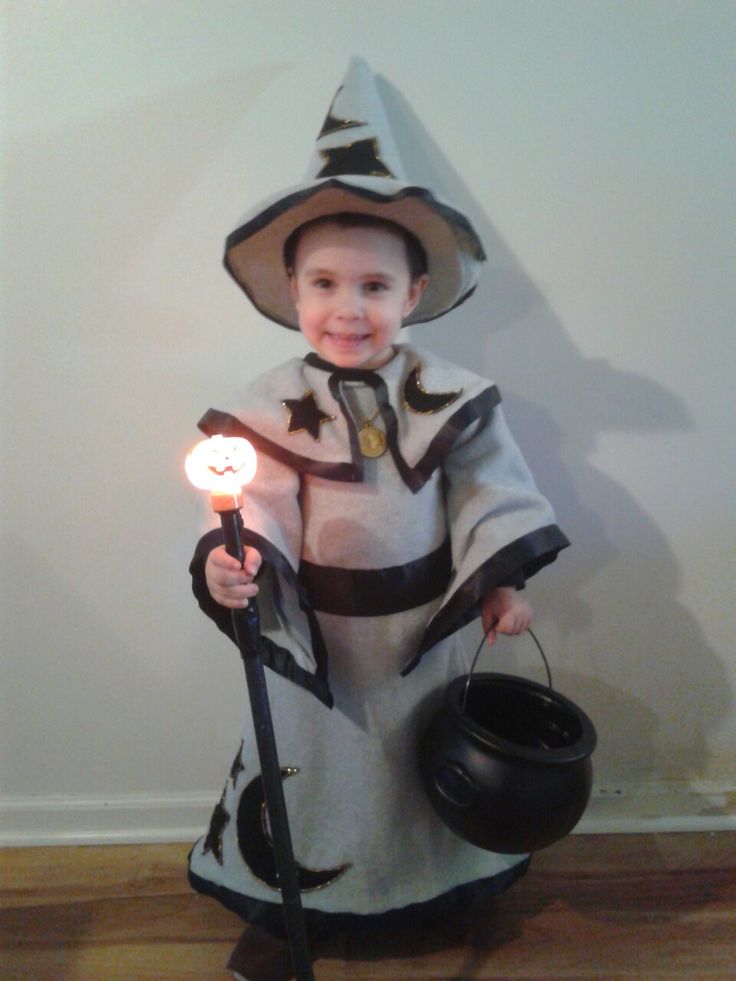 a little boy dressed up as a wizard holding a caulder and wearing a hat