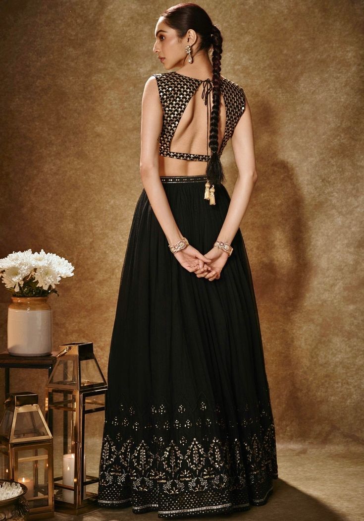 Step into the spotlight with our Black And Gold Embroidered Lehenga Set. This exquisite ensemble showcases a black and gold viscose georgette lehenga, adorned with intricate thread, dori, and sequin work. Its flattering silhouette is enhanced by pockets and cancan for added flair. The accompanying sleeveless blouse features matching scallop pattern embroidery, while a net dupatta with buttis and a handcrafted cutdana & sequin border adds a touch of elegance. Perfect for sangeet or cocktail events, this lehenga set is sure to make you the centre of attention. Composition : Lehenga, Blouse- Viscose Georgette, Dupatta - Soft Net Care: Dry Clean Only and Vacuum Storage This product can be customized for sleeves, length of blouse and neckline Delivery : 2 weeks as the product is hand crafted. C Black Embellished Sharara For Diwali, Bollywood Style Embellished Black Sharara, Black Choli With Intricate Embroidery In Georgette, Black Embroidered Sharara For Evening, Embroidered Black Sharara For Evening, Evening Embroidered Georgette Lehenga, Semi-stitched Embellished Black Sharara, Anarkali Embroidered Sharara For Evening, Anarkali Embroidered Choli For Evening