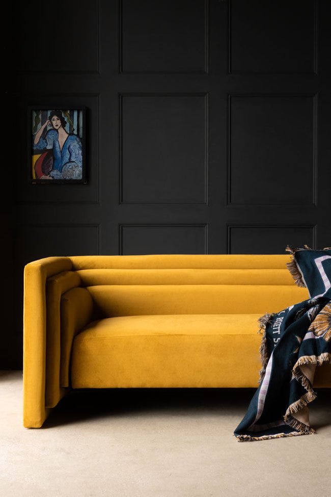 a yellow couch sitting in front of a black wall