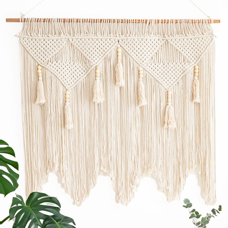 a macrame hanging on a wall next to a plant and potted plant