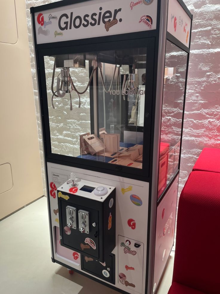 a close up of a vending machine near a red couch in a room with white walls