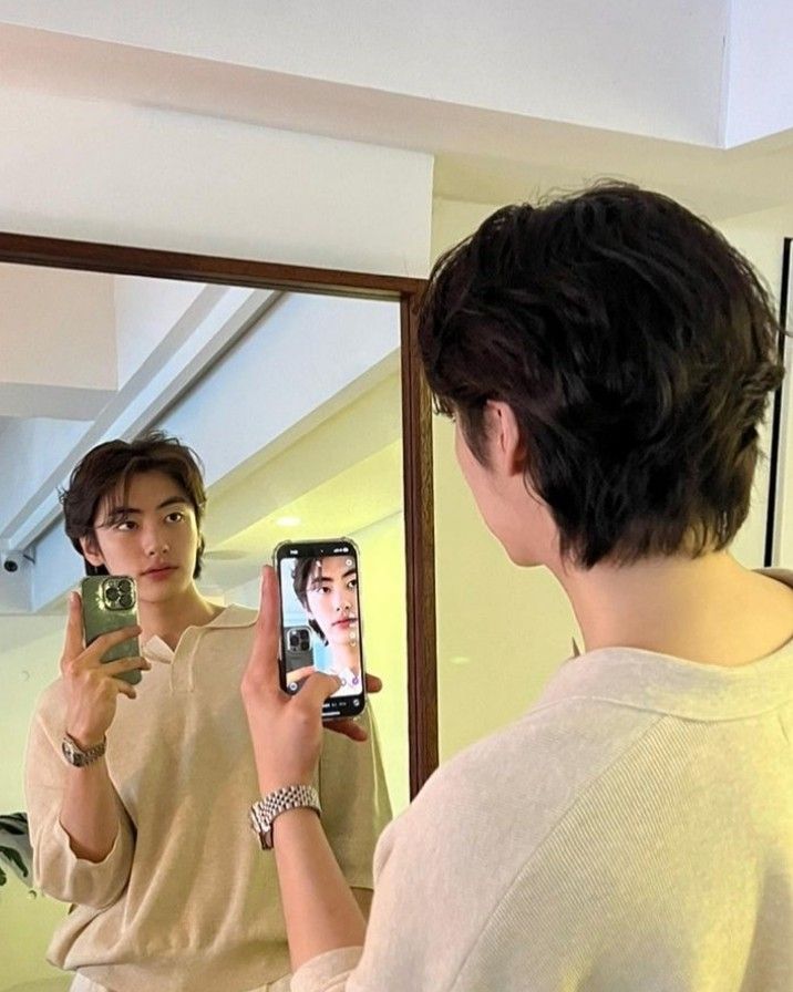 a young man is taking a selfie in front of a mirror with his cell phone