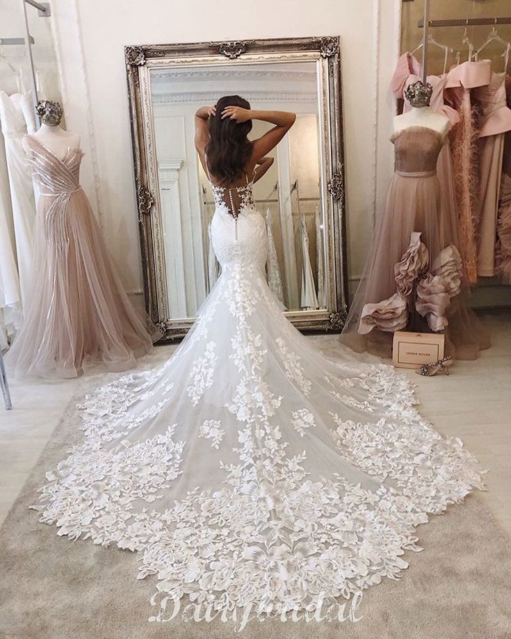 a woman standing in front of a mirror wearing a wedding dress with flowers on it