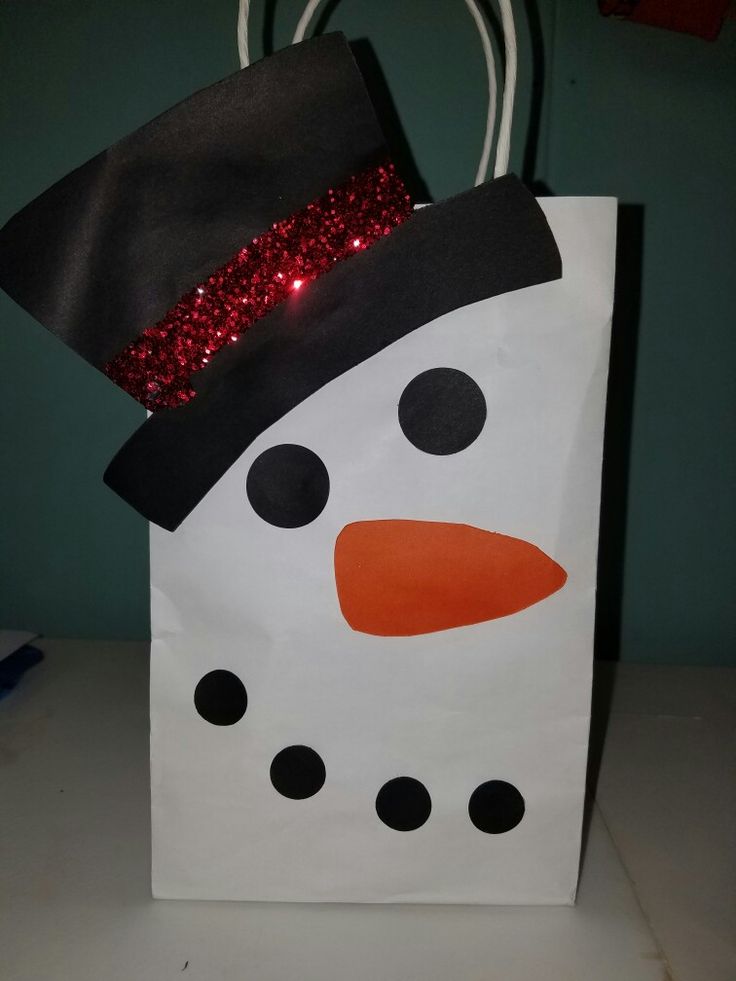 a paper bag with a snowman design on the front and red sequins on the top