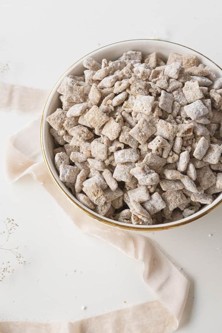 a white bowl filled with dog food on top of a table next to a cloth