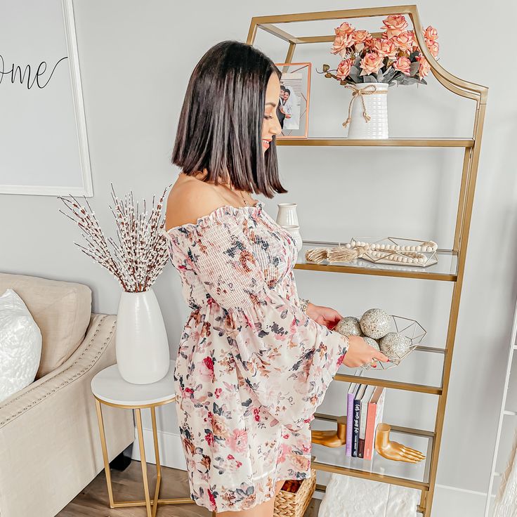 a woman standing in front of a shelf with flowers on it