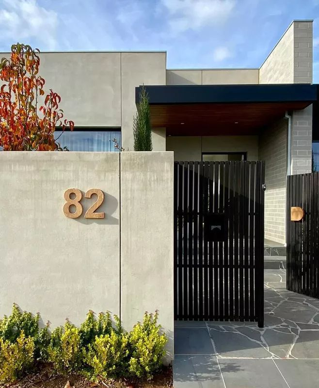 a house that has a number on the side of it and is surrounded by plants