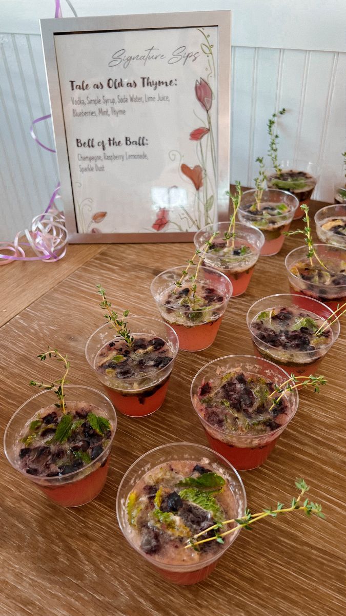 small cups filled with food sitting on top of a wooden table next to a sign