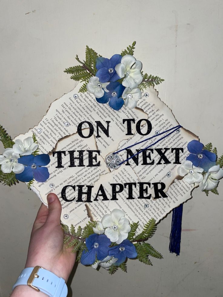 someone holding up a graduation cap that says on to the next charter with blue and white flowers