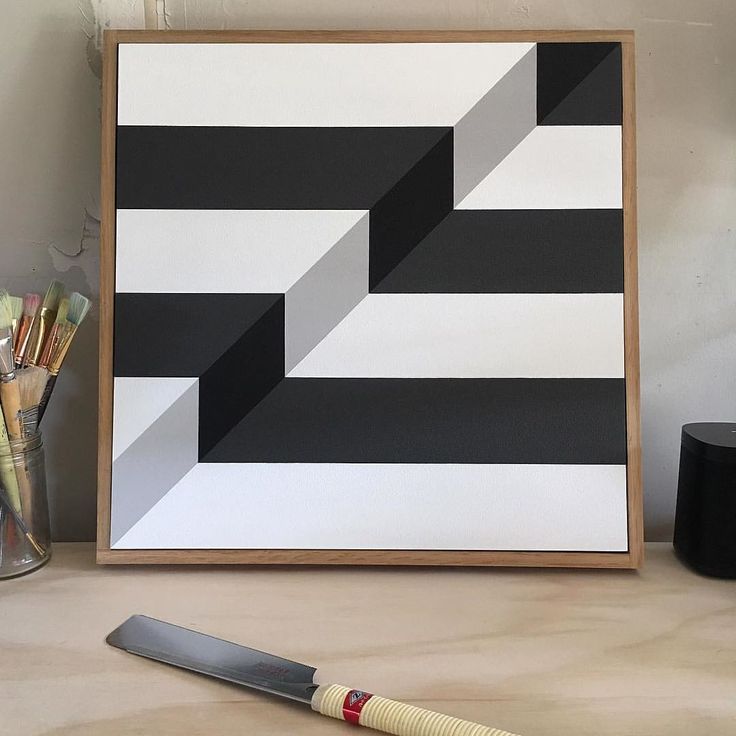 a black and white abstract painting next to a knife on a table with other art supplies