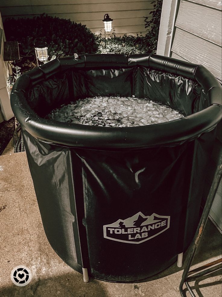 a large black trash can sitting on the side of a house