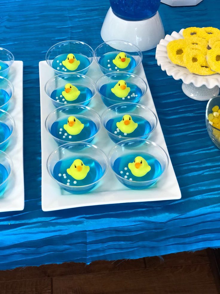 two trays filled with yellow rubber ducks next to blue table cloth and dessert plates