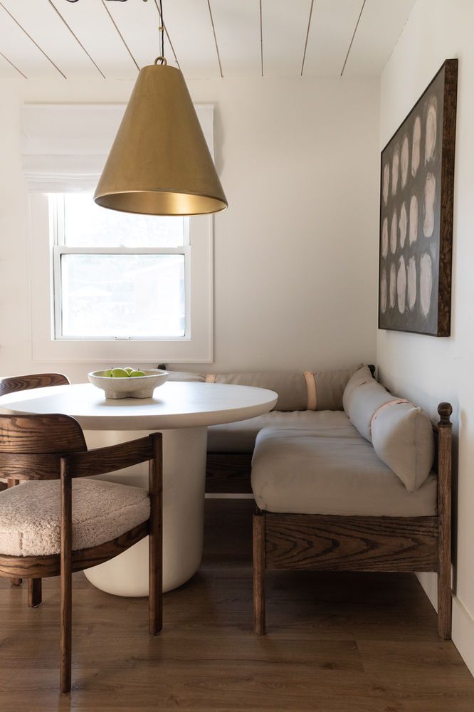 a white table and chairs in a room with wood flooring next to a window