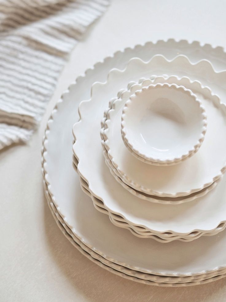 a stack of white plates sitting on top of a table next to a cloth napkin