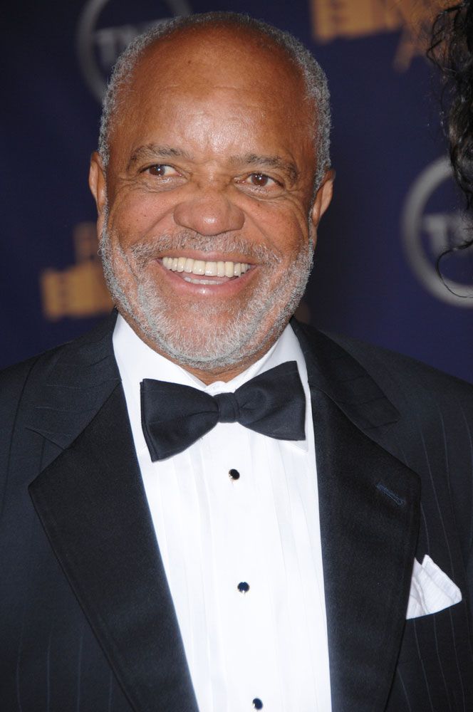 an older man in a tuxedo and bow tie smiles at the camera while wearing a black suit