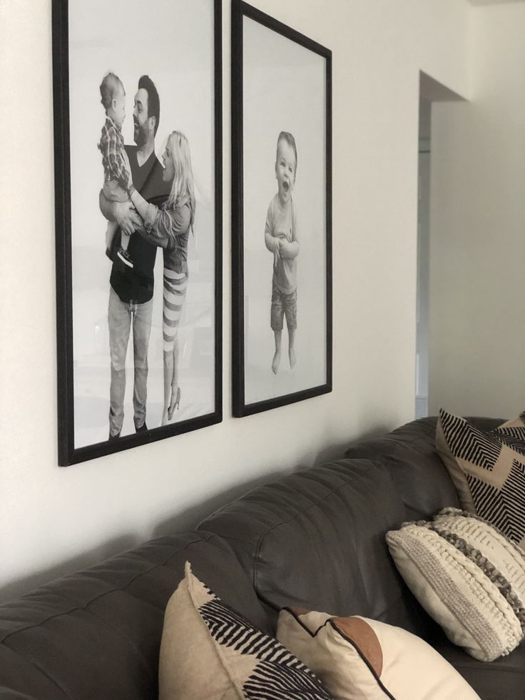 two black and white pictures hang on the wall above a couch with pillows, blankets and throw pillows