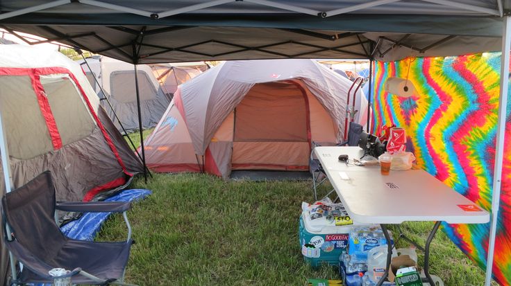 several tents set up in the grass with one tent on top and two chairs under it