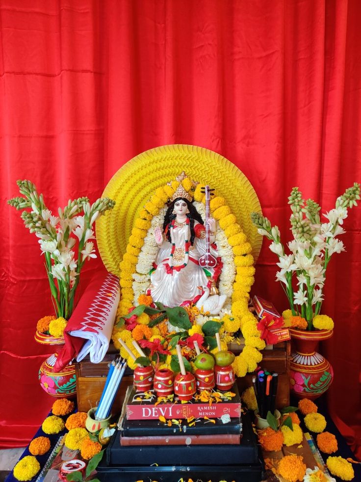 there is a shrine with flowers and candles on the table in front of red curtains