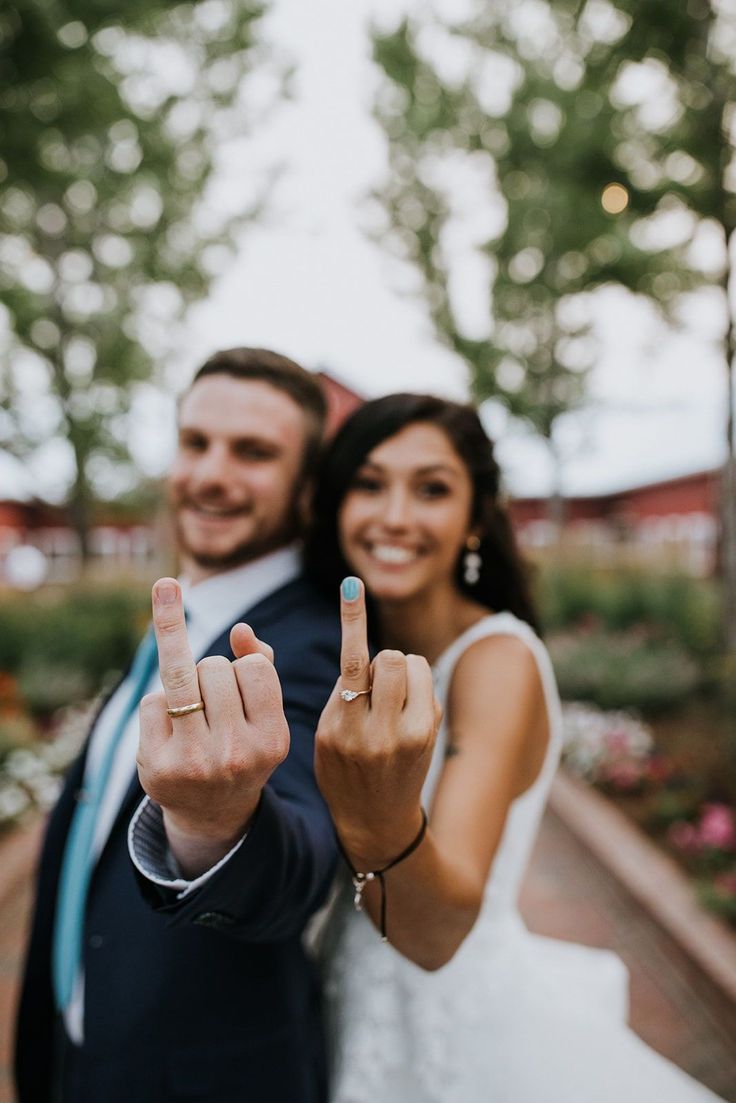 a bride and groom holding up their fingers in front of the camera with peace signs