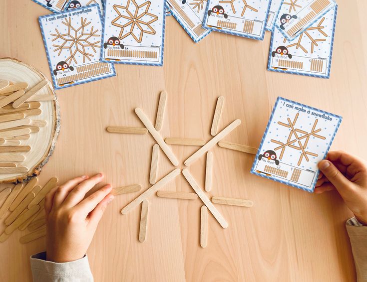 a person making snowflakes out of popsicle sticks on a wooden table with other stick decorations