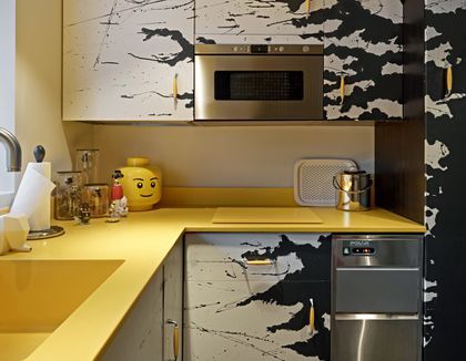 a kitchen with yellow counter tops and white cabinets, including a stainless steel microwave oven