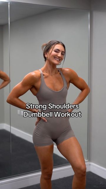 a woman standing in front of a mirror with her hands on her hips and arms behind her back