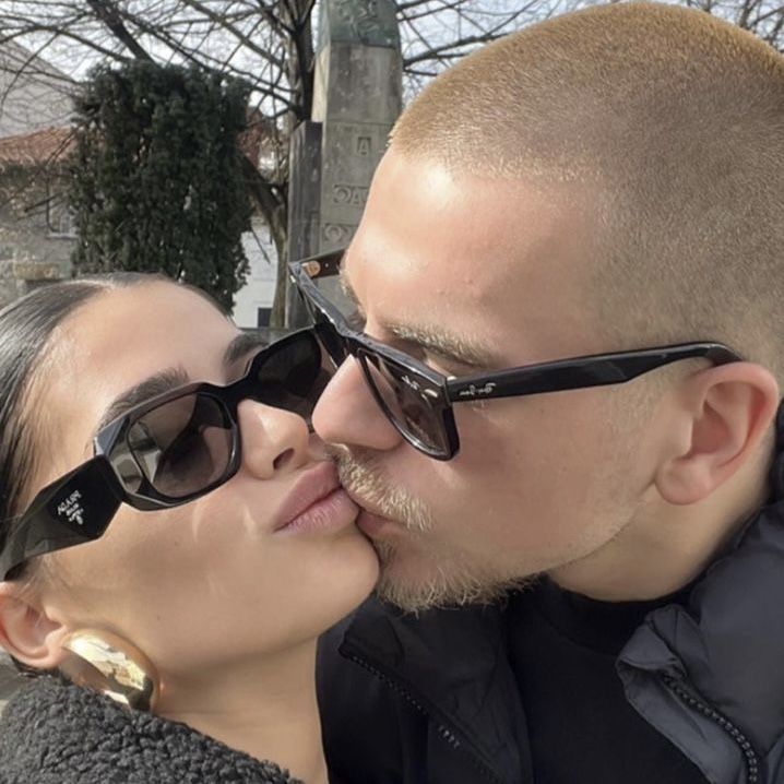 a man and woman kissing each other while wearing sunglasses