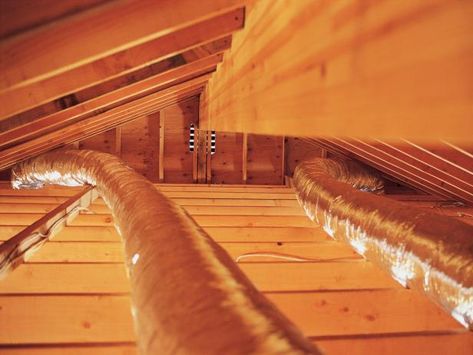 an attic with wood flooring and exposed pipes in the ceiling, viewed from below