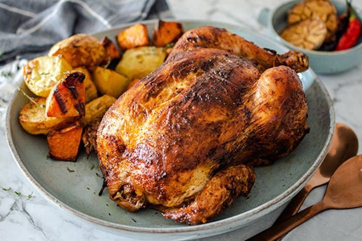 a roasted chicken on a plate with potatoes and carrots next to the rest of the dish