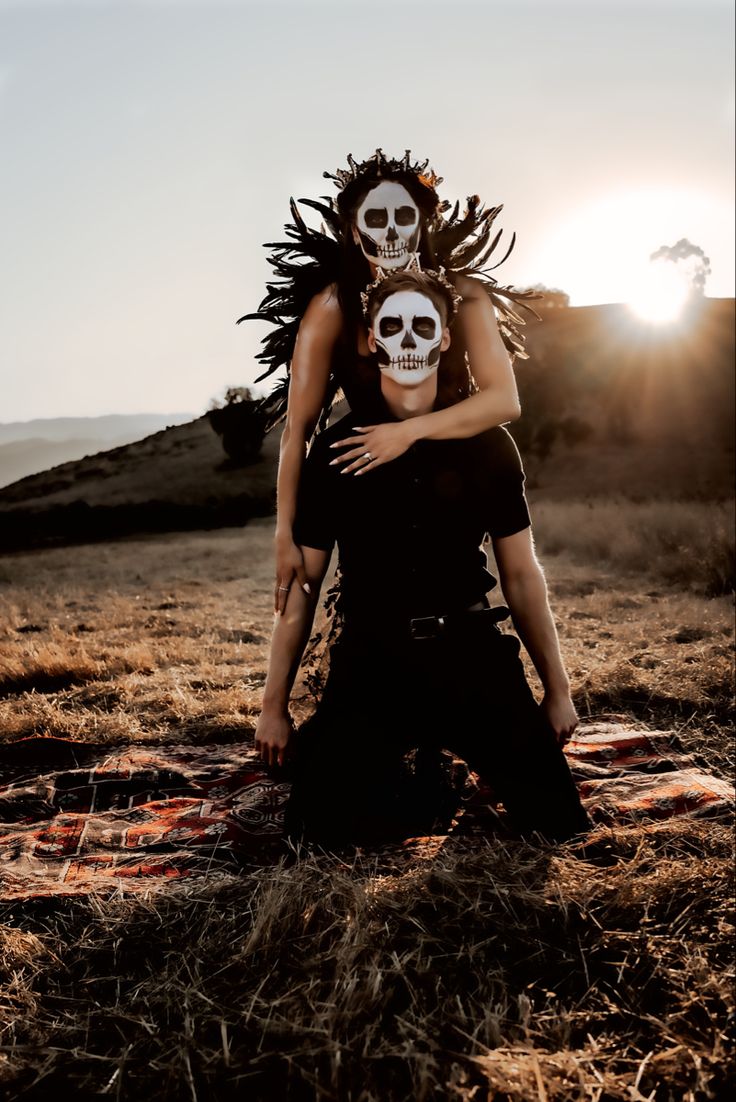 two people with skull makeup are sitting on a blanket