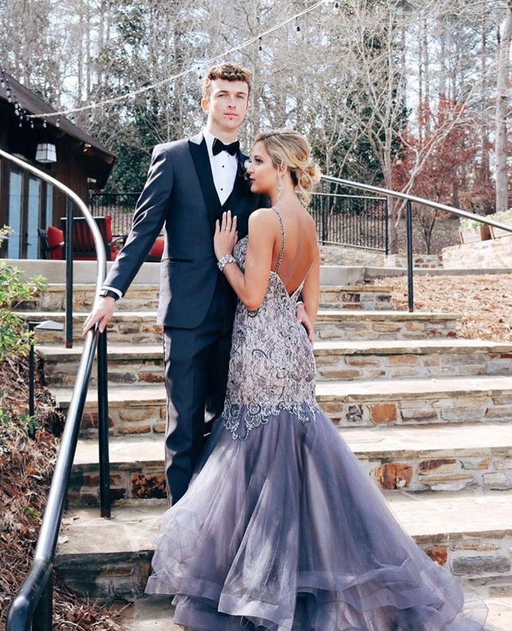 a man and woman in formal wear standing on steps