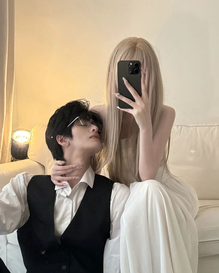 a man and woman taking a selfie in front of a white couch