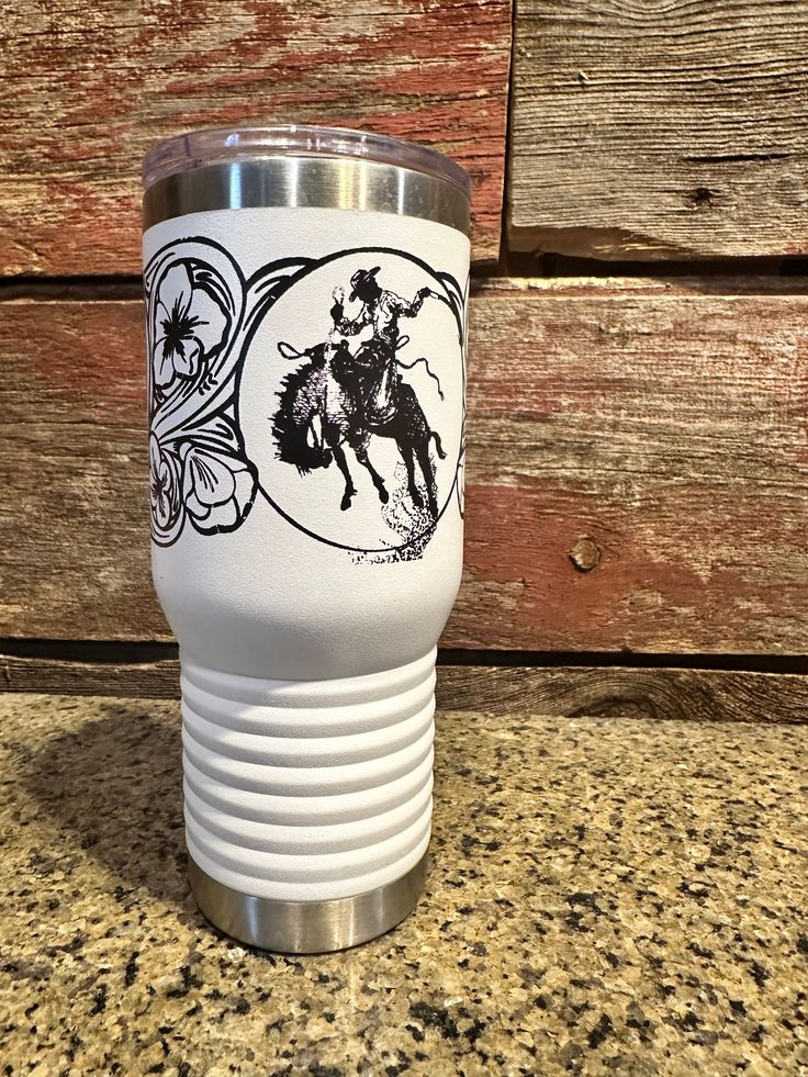 a white tumbler cup with a black and white image of a cowboy on it