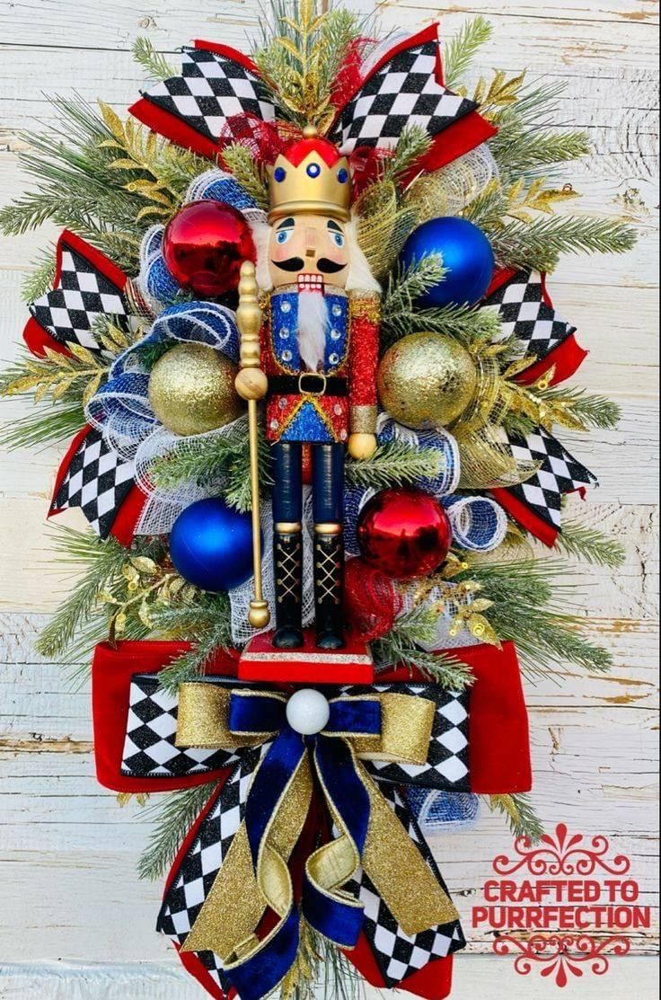 a christmas wreath with a nutcracker and ornaments hanging from it's side