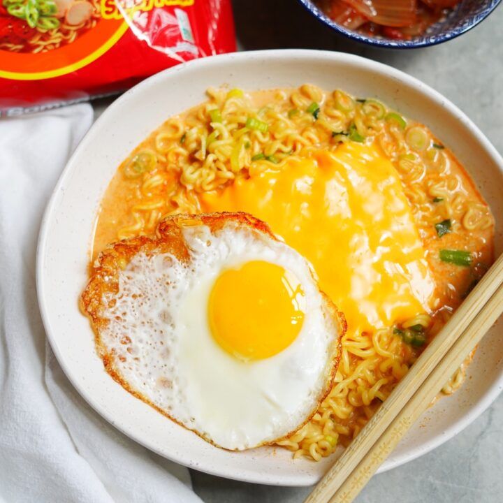 a bowl with noodles, egg and chopsticks next to a bag of ramen