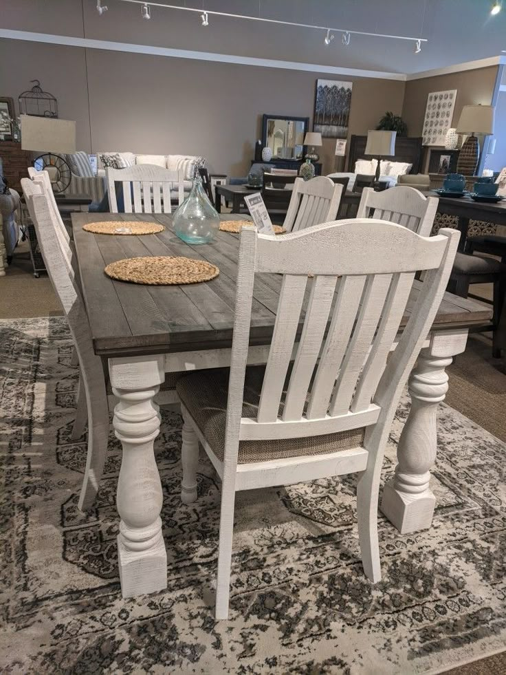 a dining room table with chairs and place mats on the rug in front of it