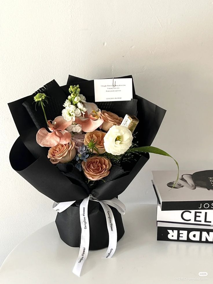 a bouquet of flowers sitting on top of a table next to a box of books